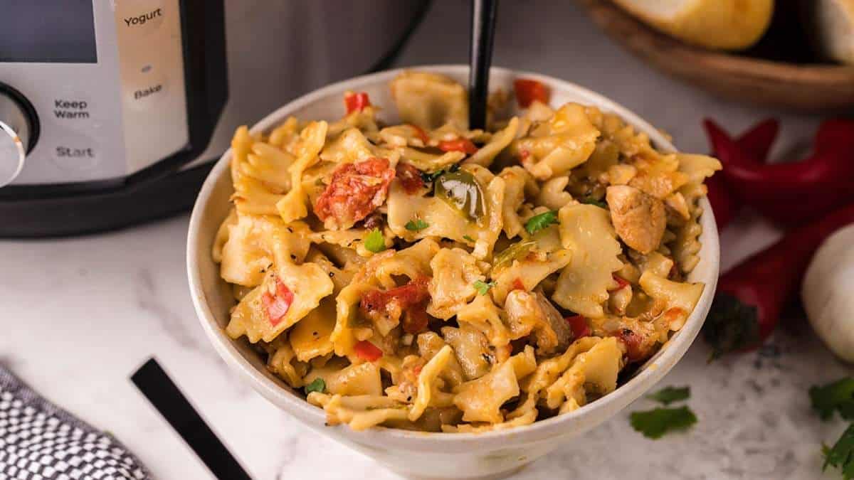 A bowl of pasta in front of an instant pot.
