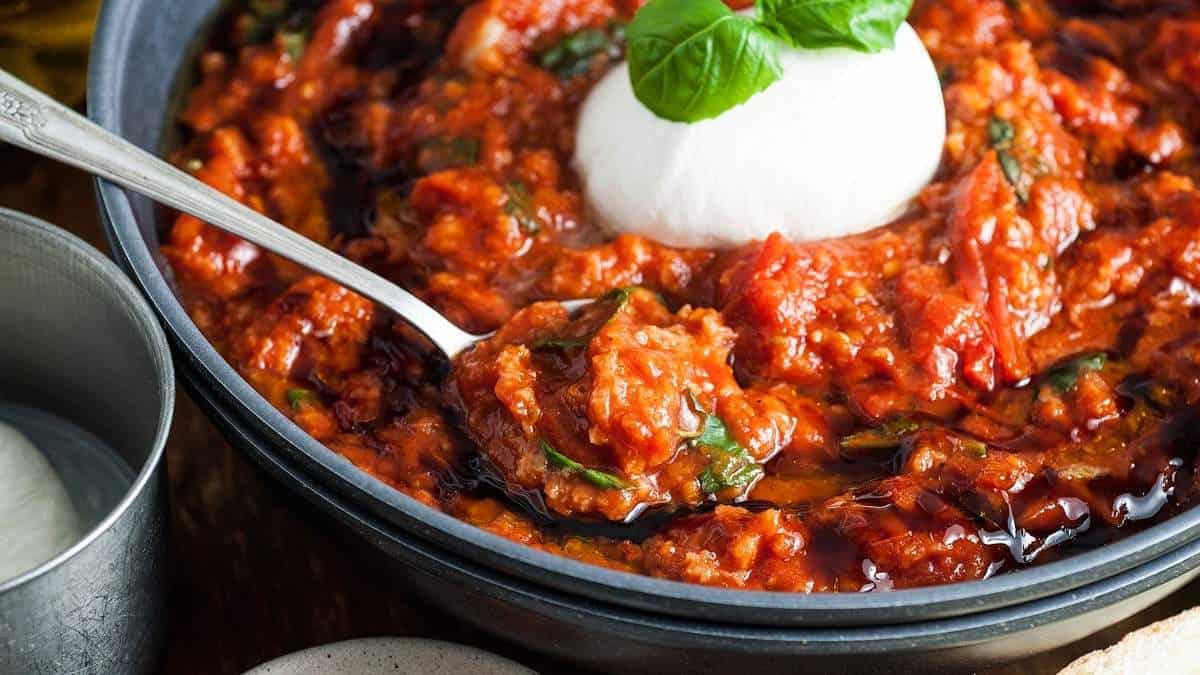 A bowl of tomato sauce with a spoon and a bowl of sour cream, perfect for soup recipes.