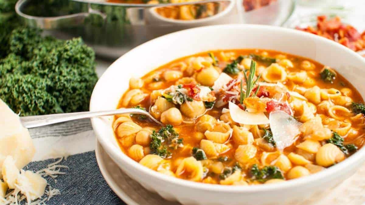 A bowl of soup with a spoon made from pasta and kale.