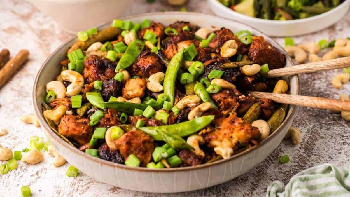 A bowl filled with chicken, cashews and green beans.