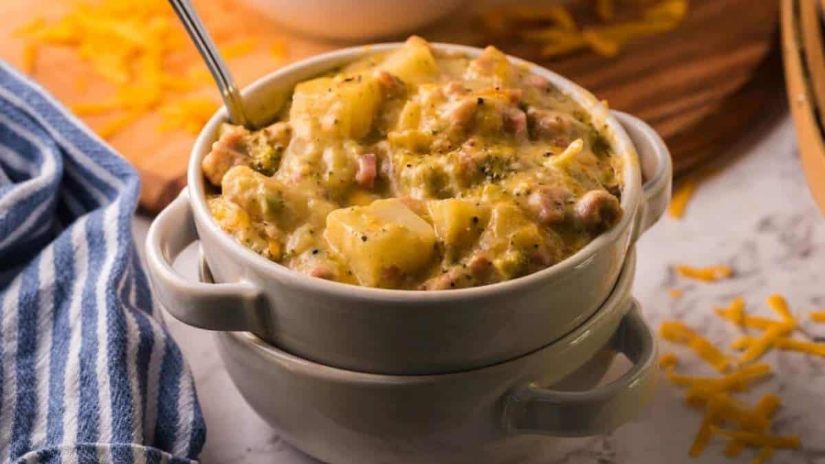 Cheesy potato casserole in a white bowl with a spoon, perfect for hearty soup recipes.