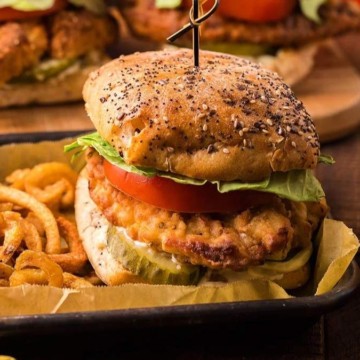 Chicken burgers with fries and ketchup on a wooden table.