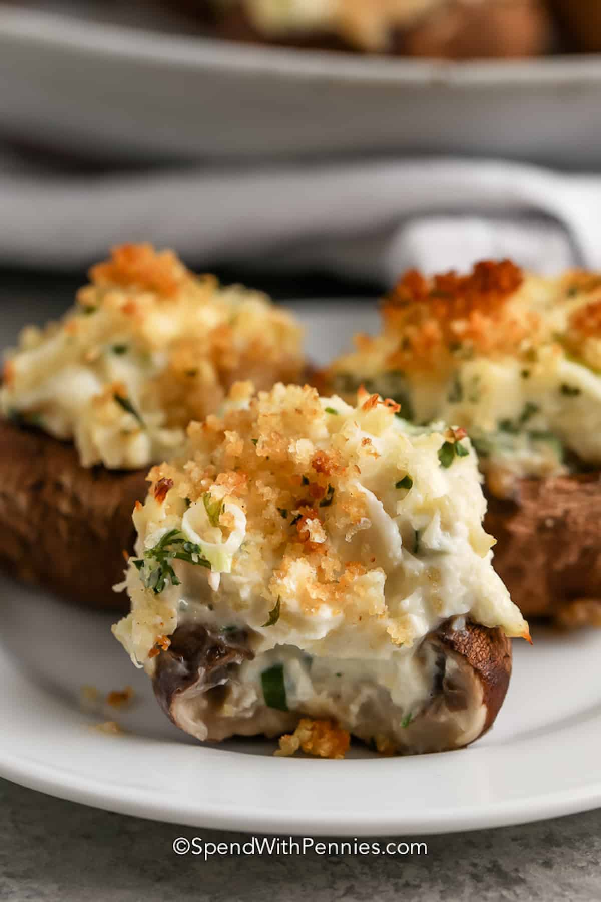 Stuffed mushrooms with parmesan cheese and parsley, served on a white plate.