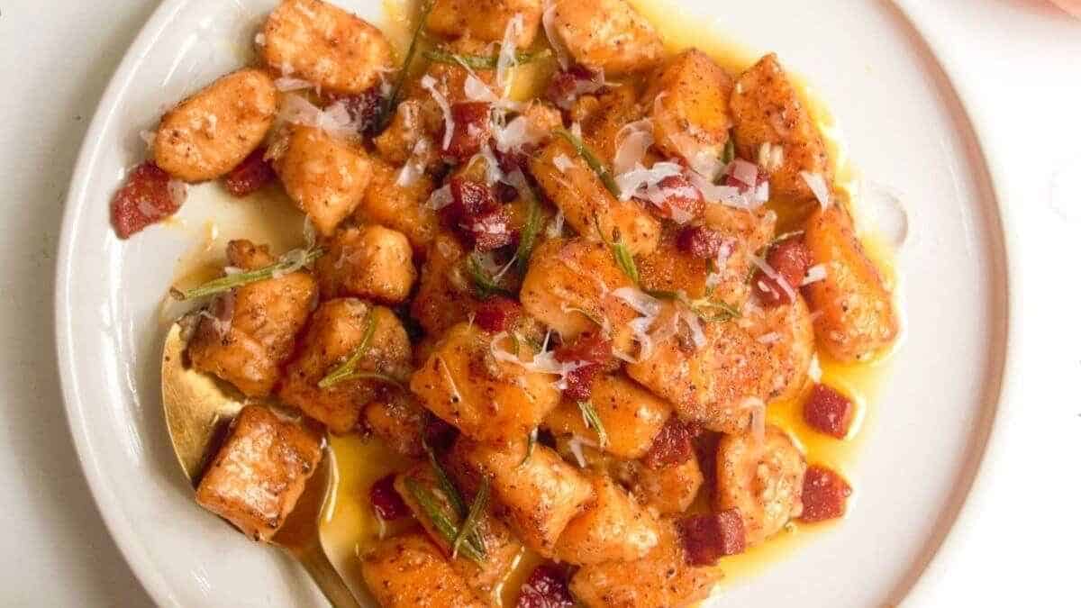A plate of gnocchi with bacon and rosemary.