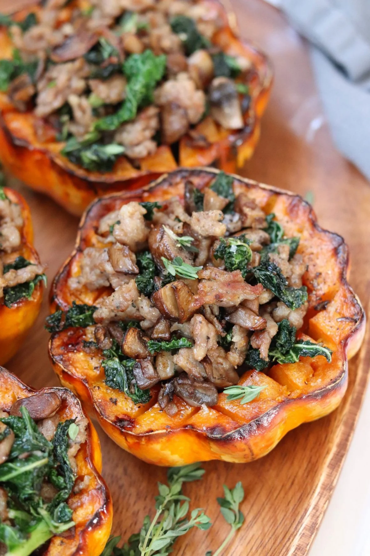 Sausage-stuffed squash with mushrooms and spinach on a wooden cutting board.