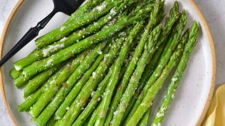 Grilled asparagus on a plate with a fork.
