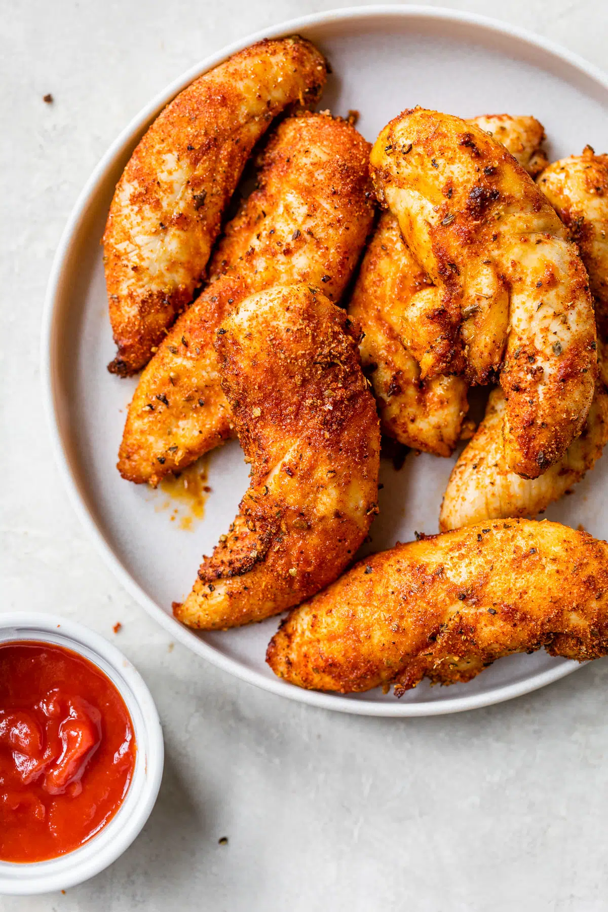 Chicken wings on a plate with ketchup on the side, perfect for chicken tender recipes.