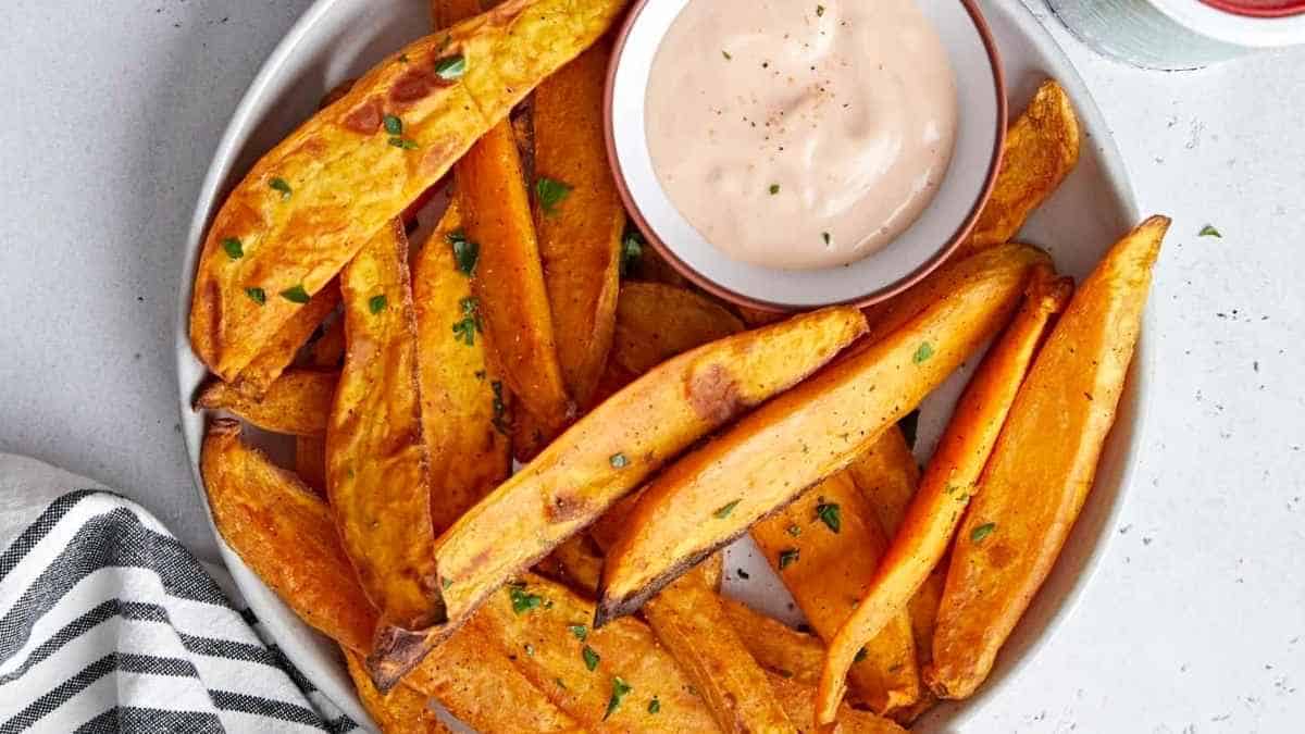 Sweet potato fries on a plate with dipping sauce.