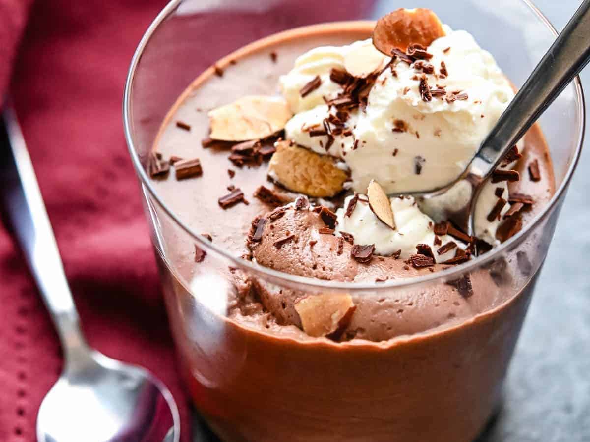 Chocolate mousse in a glass with whipped cream and a spoon.