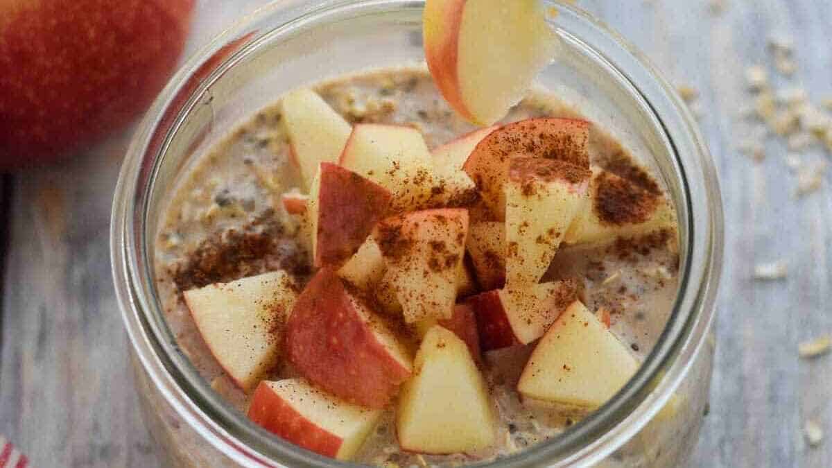 A jar of oatmeal with apples and cinnamon.
