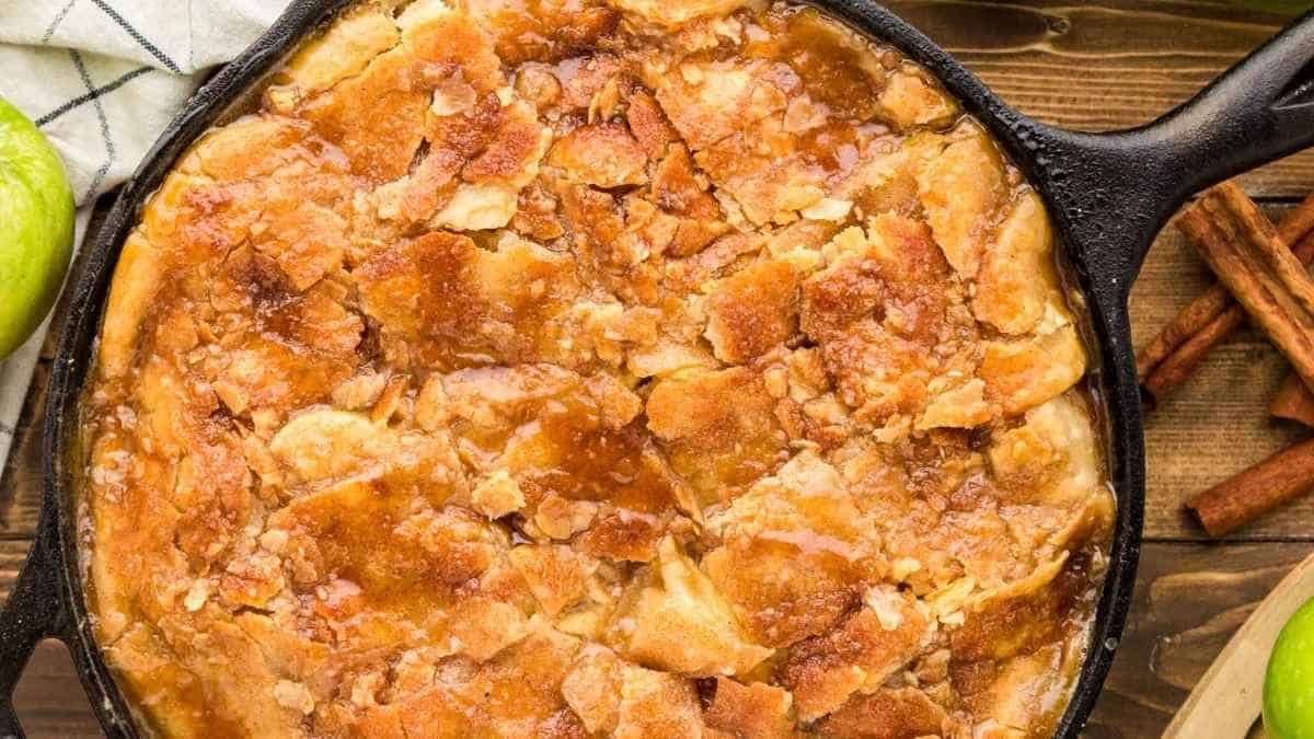 Apple cobbler in a cast iron skillet on a wooden table.