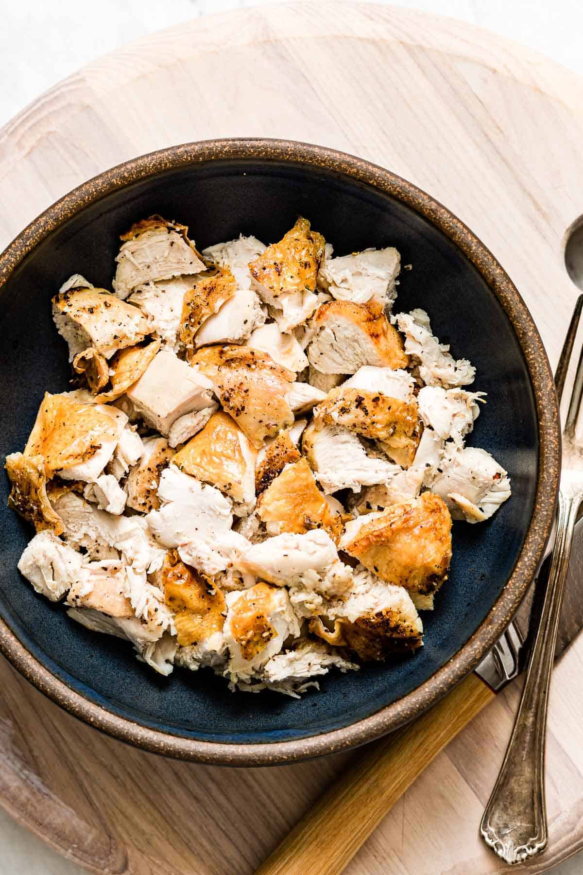 Bone-in chicken breast served in a blue bowl, accompanied by a fork.