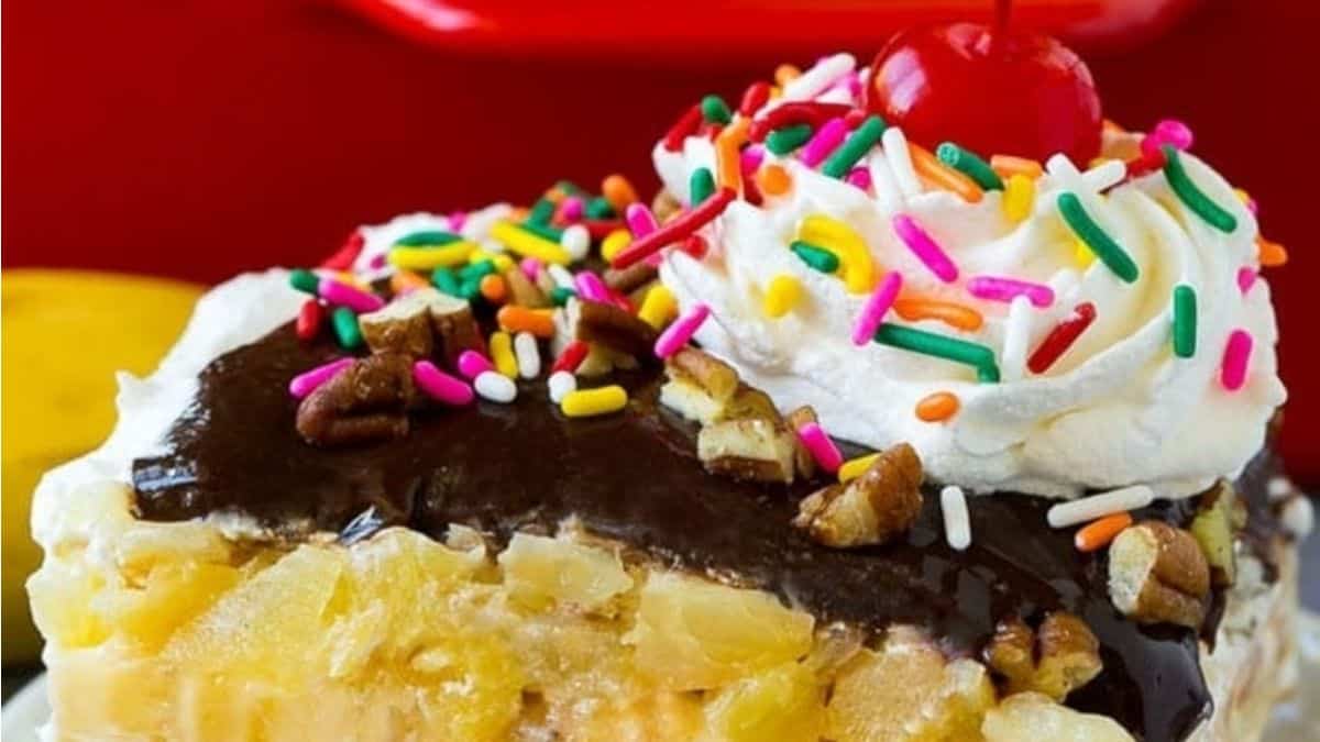 A slice of banana cake with chocolate icing and sprinkles.