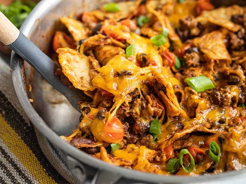 Mexican nachos in a pan with a wooden spoon.