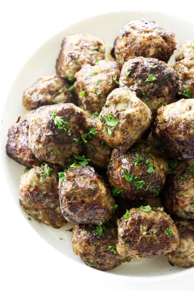 A plate of meatballs made with ground sausage and garnished with parsley.