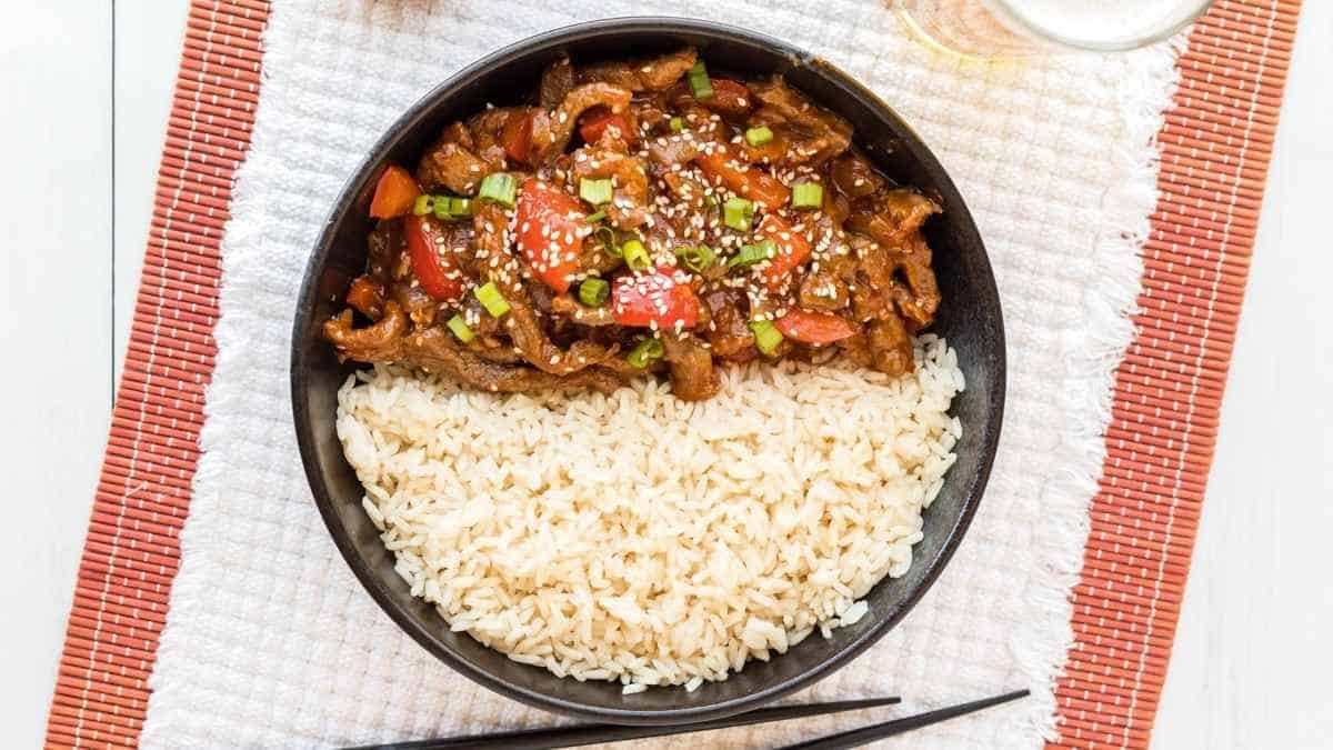 A bowl of rice and meat on a table.