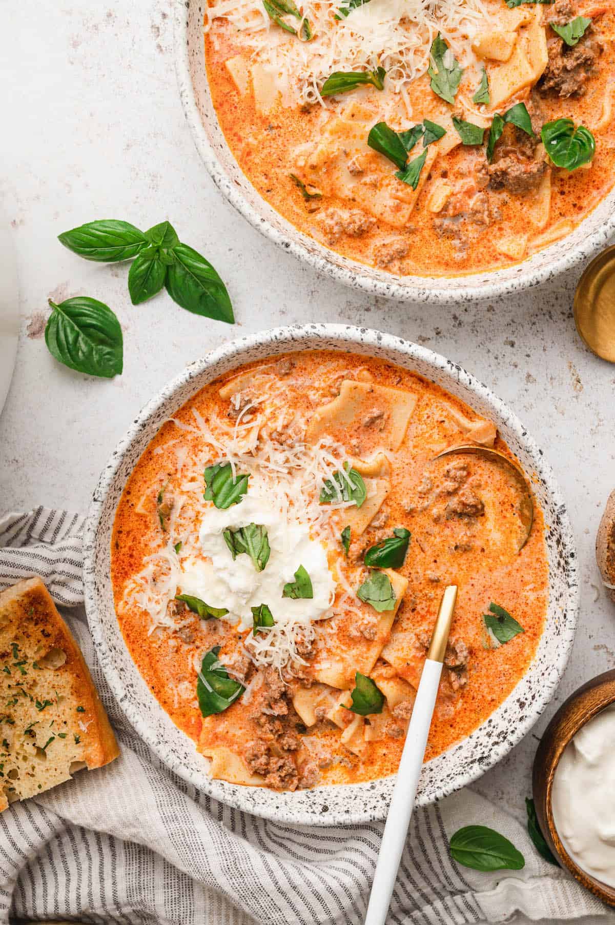 Two bowls of meatball soup with ground sausage, sour cream and basil.