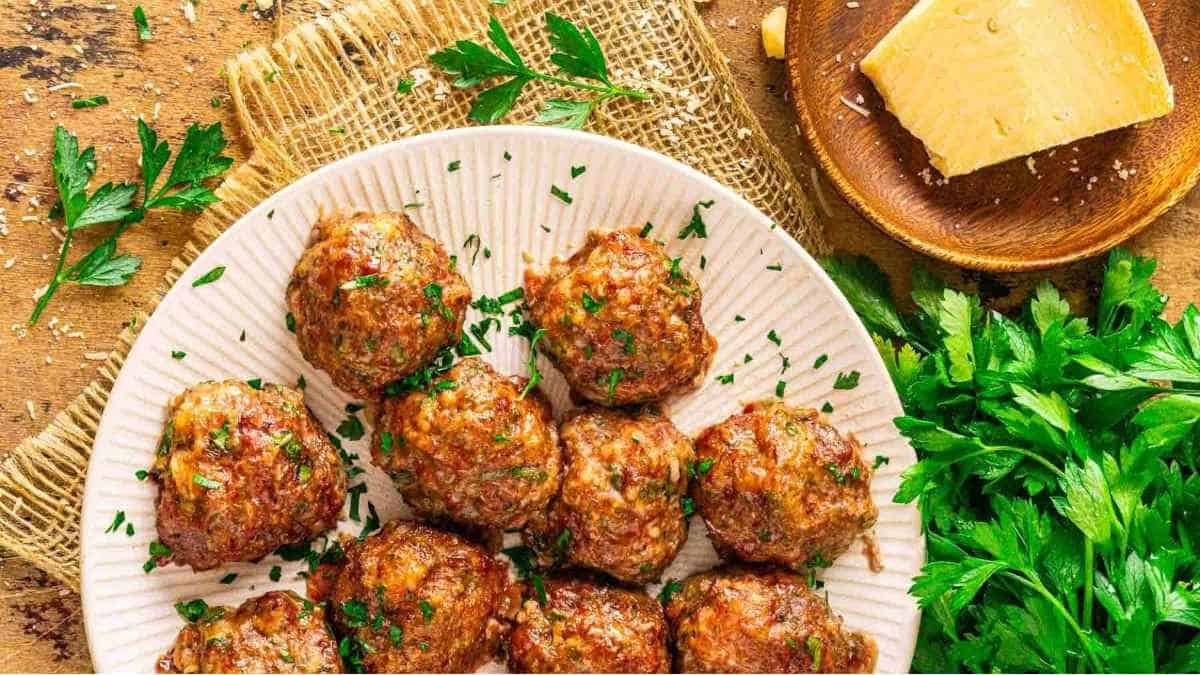 Meatballs on a plate with parsley and cheese.