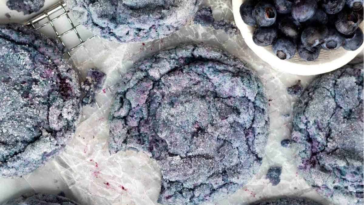 Blueberry cookies on a baking sheet with blueberries.