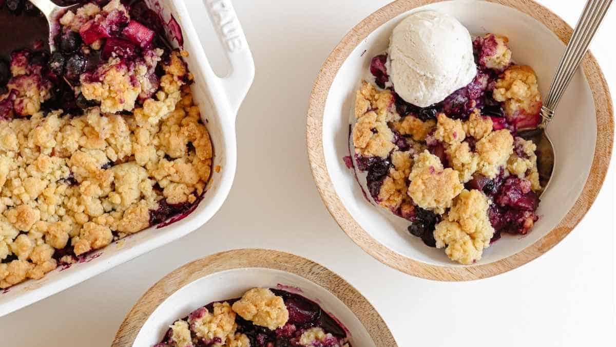 Two bowls of blueberry crumble with ice cream.
