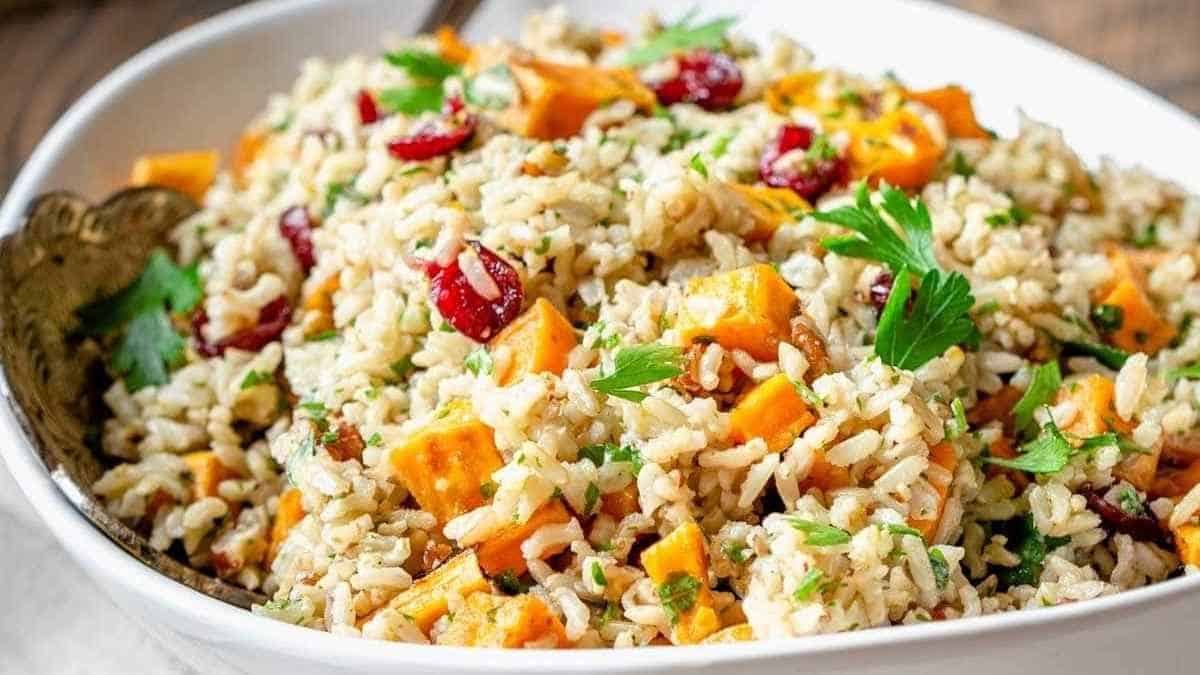 A white bowl filled with rice, carrots and cranberries.