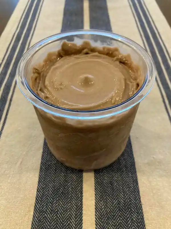 A cup of peanut butter sitting on a table.