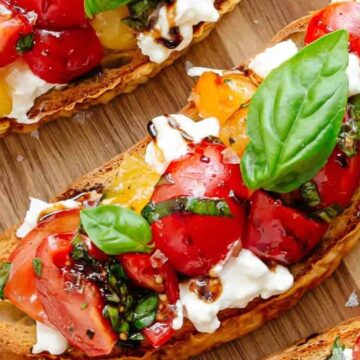 Sliced bread with tomatoes and basil on it.