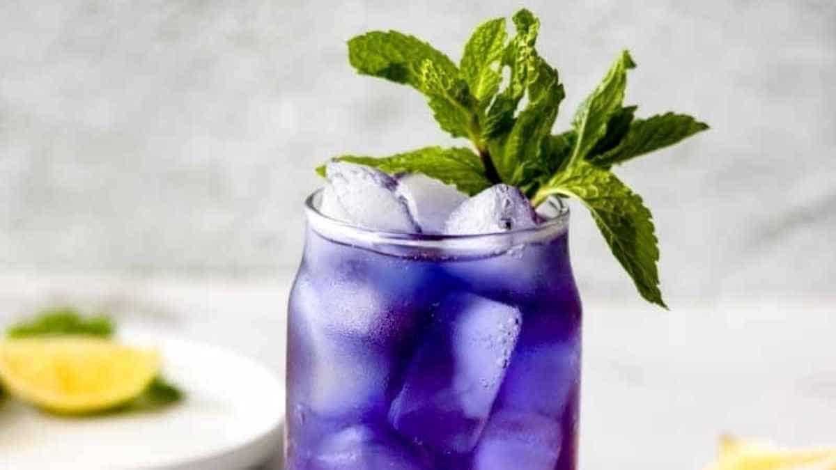 A purple drink with mint leaves and ice.