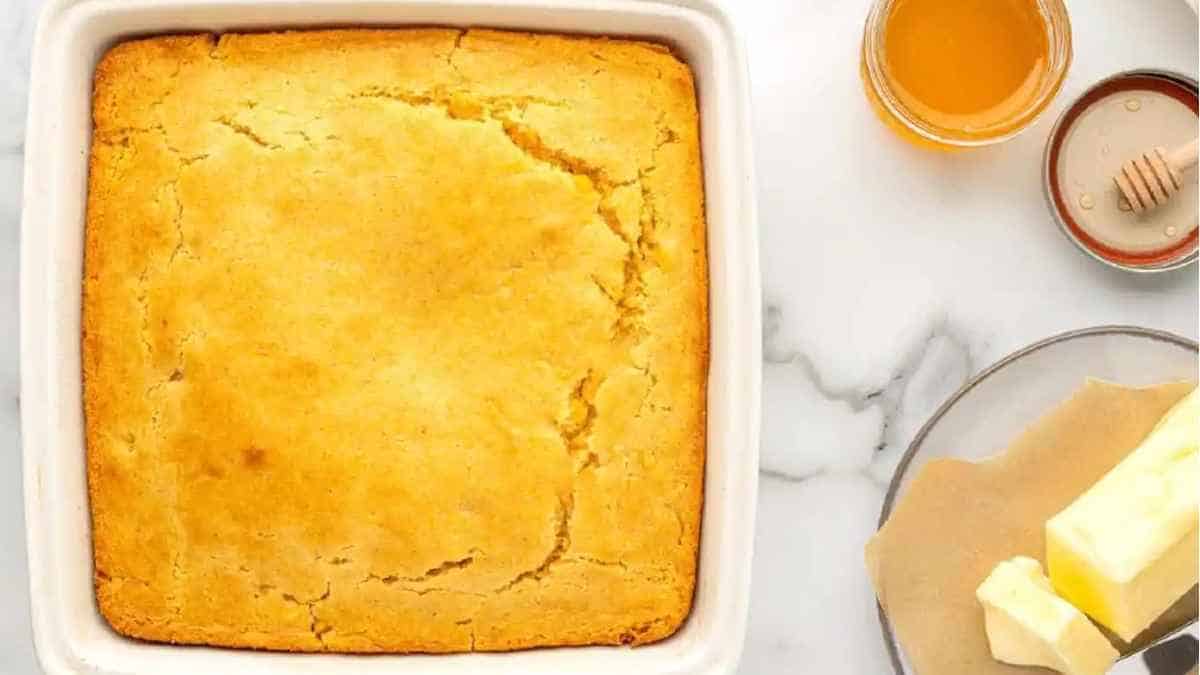 Cornbread in a baking dish with butter and honey.