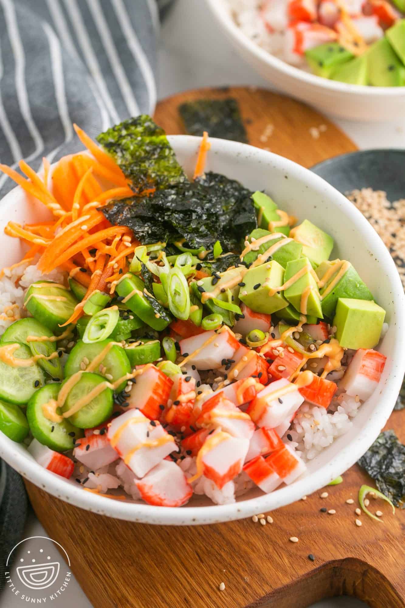 A vibrant Asian noodle bowl filled with fresh vegetables and topped with imitation crab.