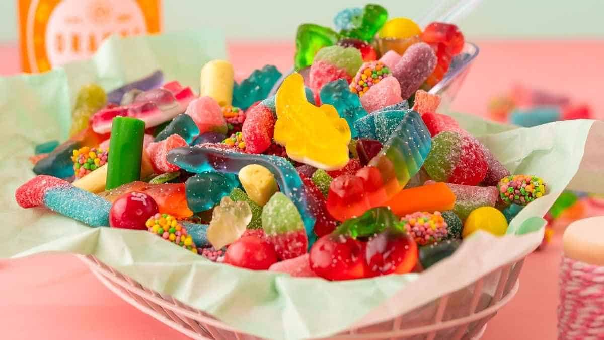 A basket full of gummy candies on a pink table.