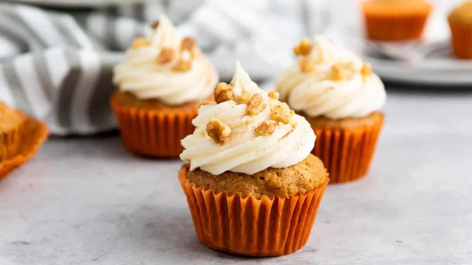 Pumpkin cupcakes with whipped cream and walnuts.