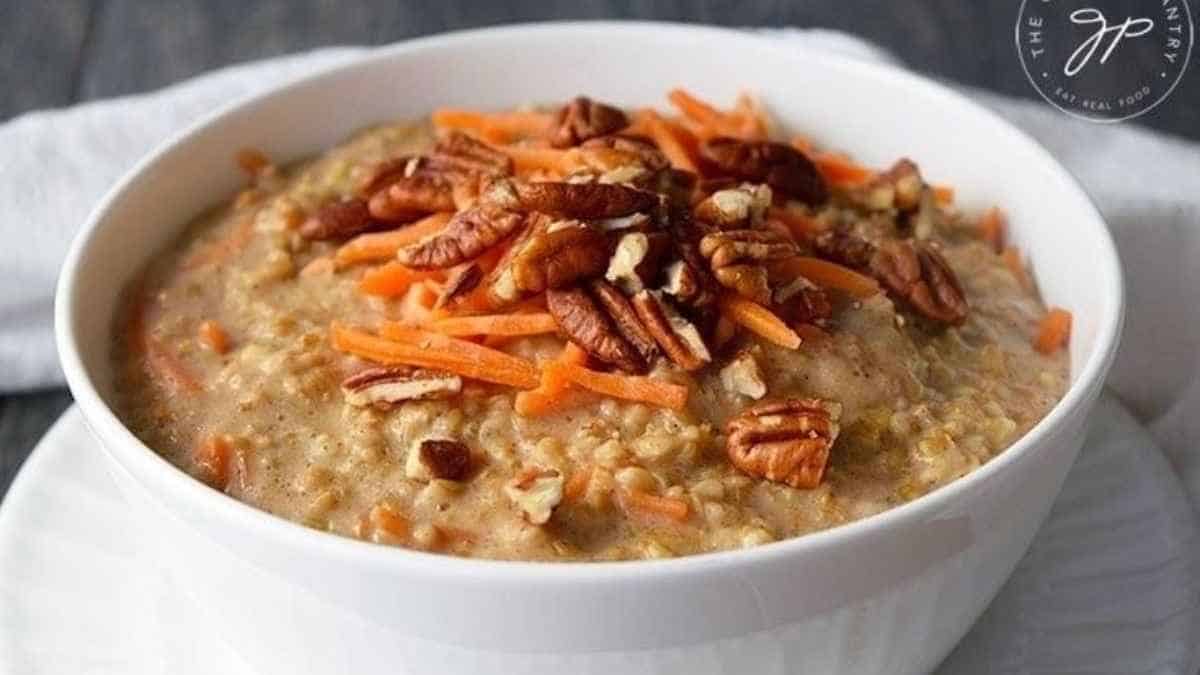 A bowl of oatmeal with carrots and pecans.