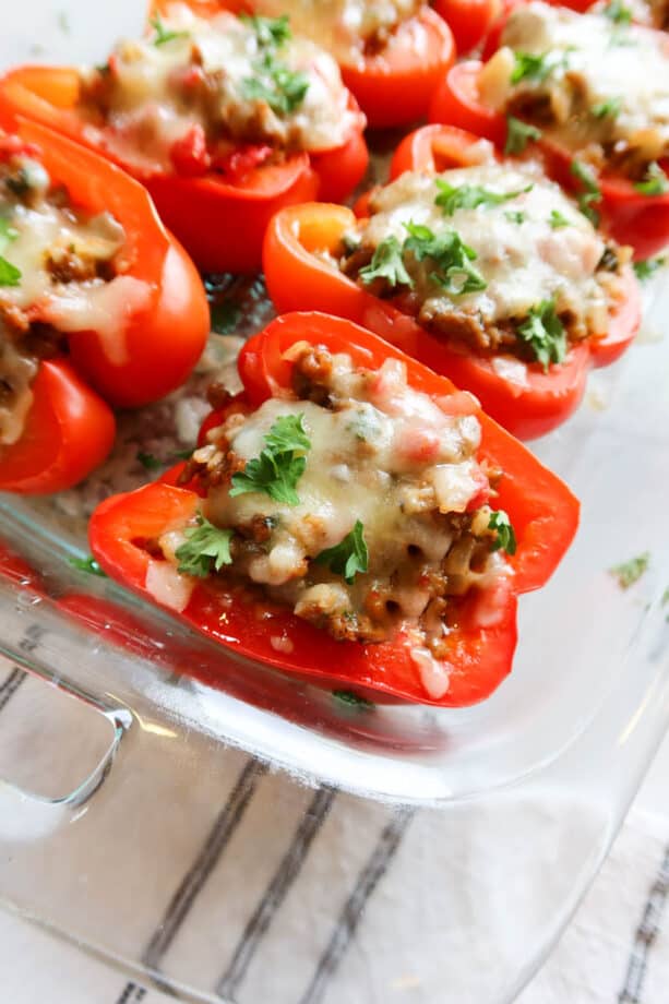 Sausage stuffed peppers with meat and cheese in a glass dish.