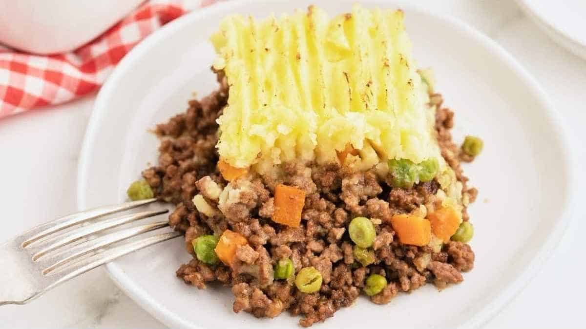 A piece of meat and potato pie on a plate with a fork.