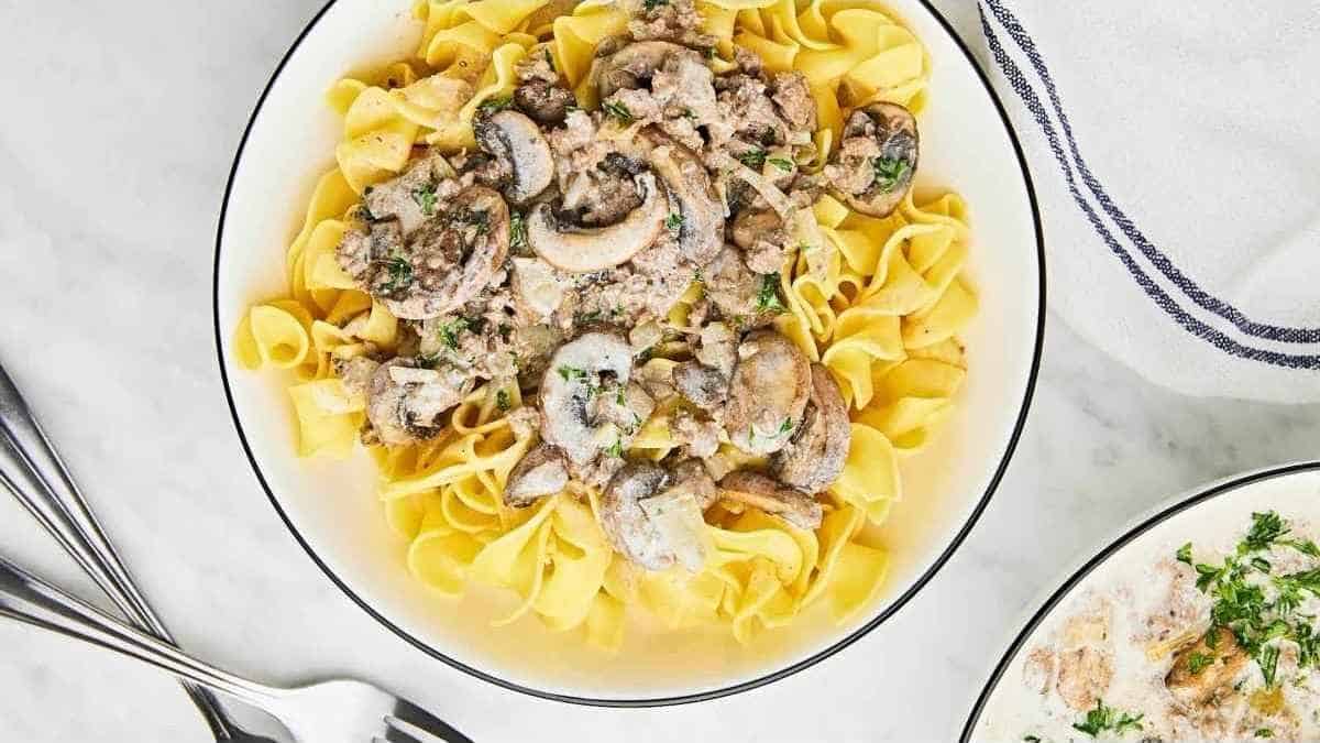 A bowl of pasta with mushrooms and parsley.