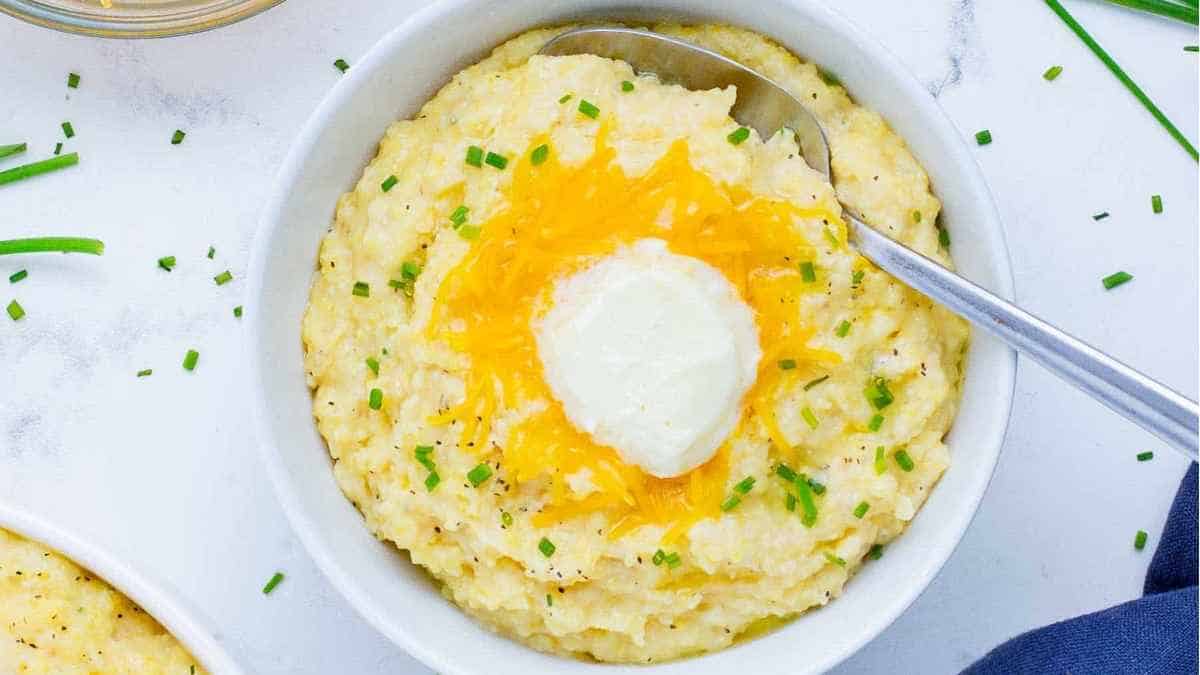 Mashed potatoes in a bowl with a spoon and chives.