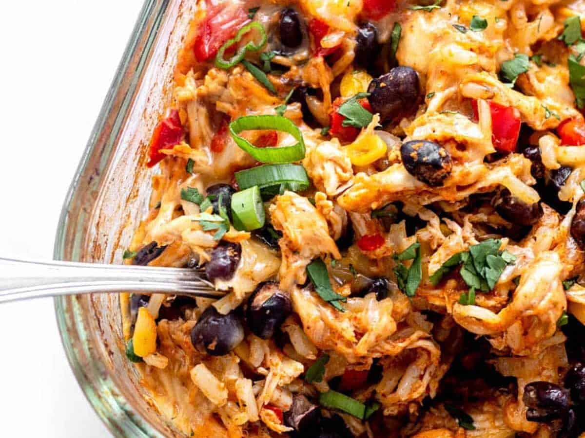 Mexican chicken casserole in a glass dish with a spoon.