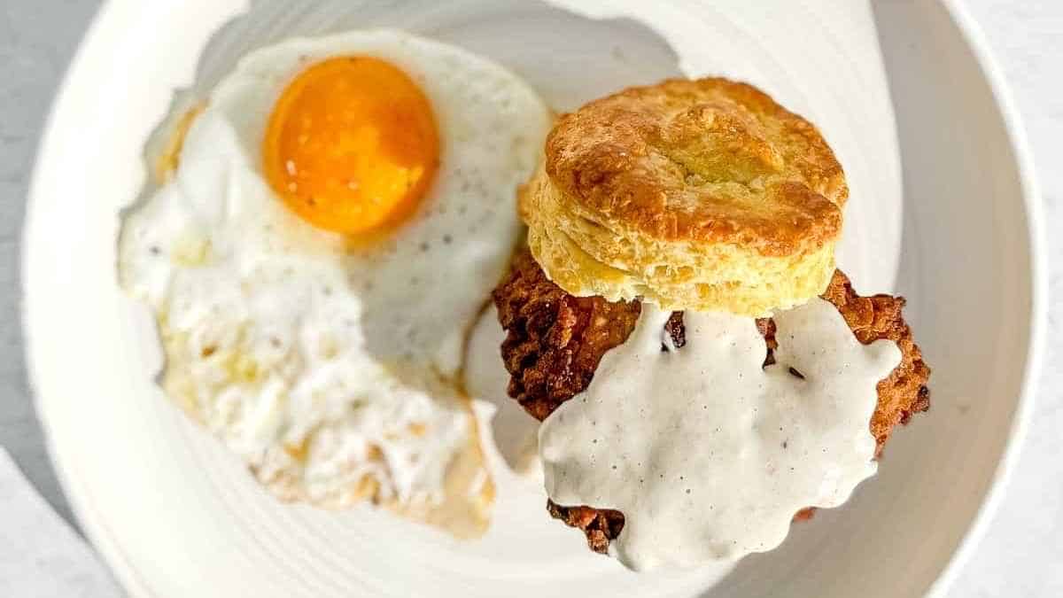 A plate of biscuits and gravy with an egg on it.