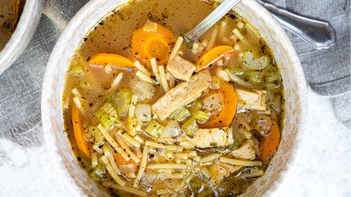 A bowl of chicken noodle soup with carrots and noodles.