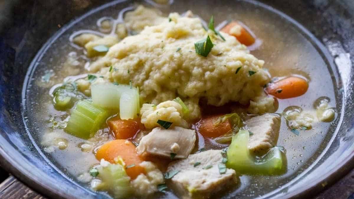 A bowl of soup with chicken and vegetables.