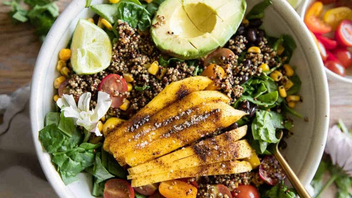 A bowl of quinoa salad with avocado and tomatoes.