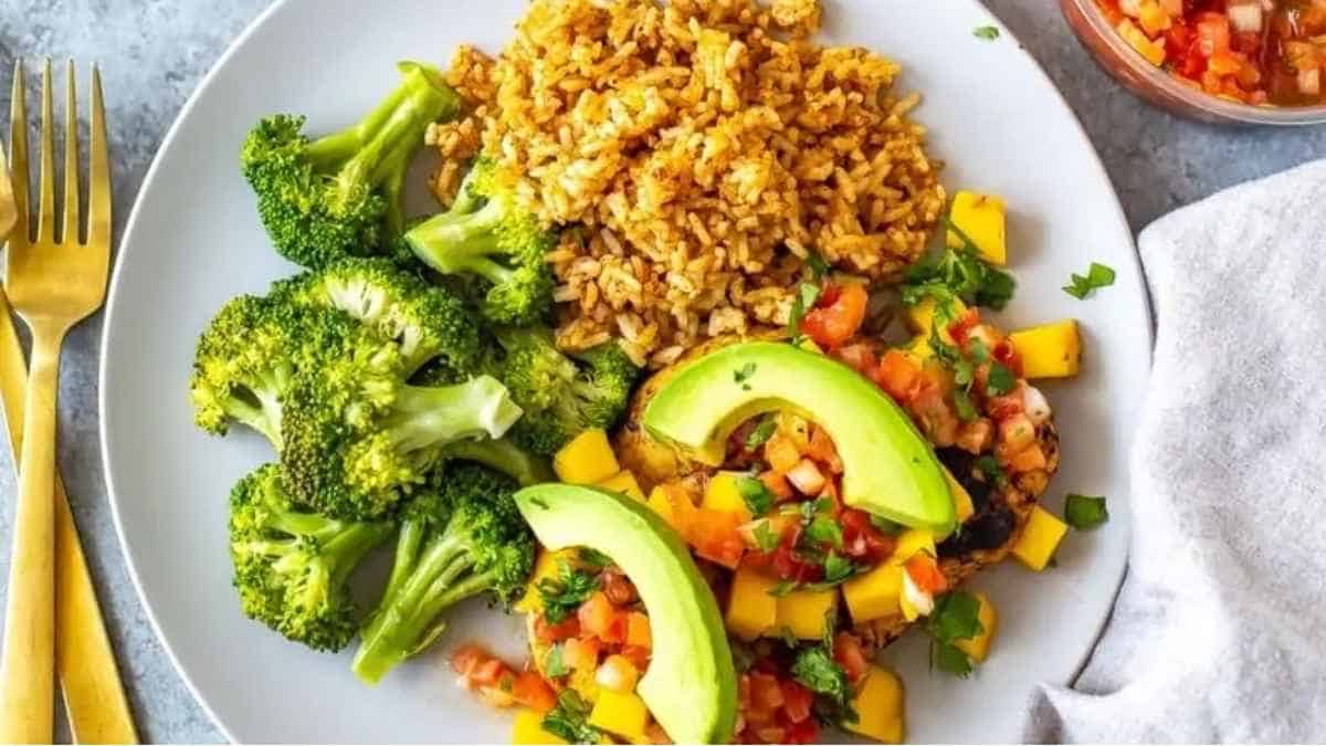A plate with rice, broccoli and avocado.
