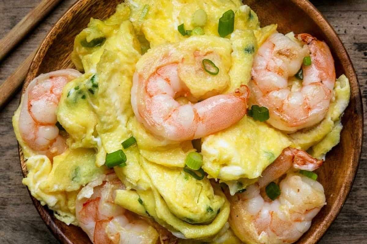 Shrimp and eggs in a wooden bowl with chopsticks.