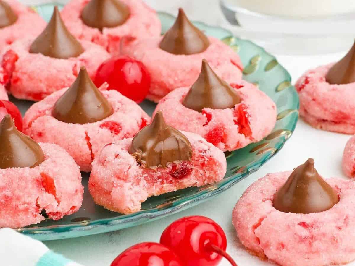 A plate of pink cherry cookies with chocolate kisses on top.