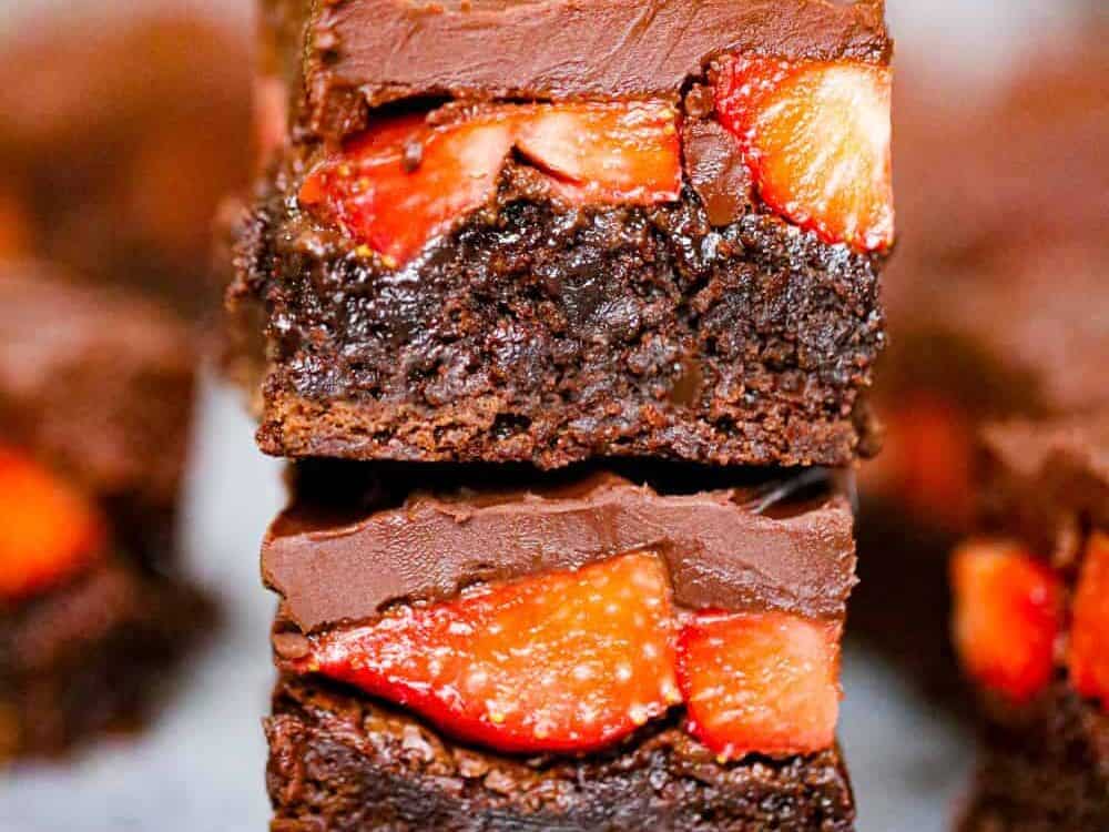 A stack of chocolate brownies with strawberries on top.