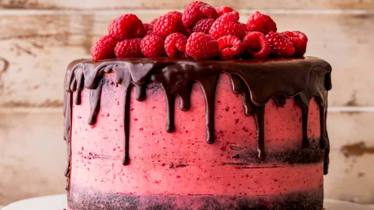Raspberry ice cream cake on a wooden stand.