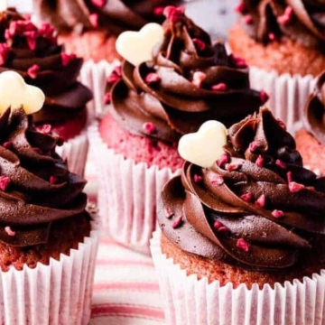 Chocolate cupcakes topped with chocolate frosting and raspberries.
