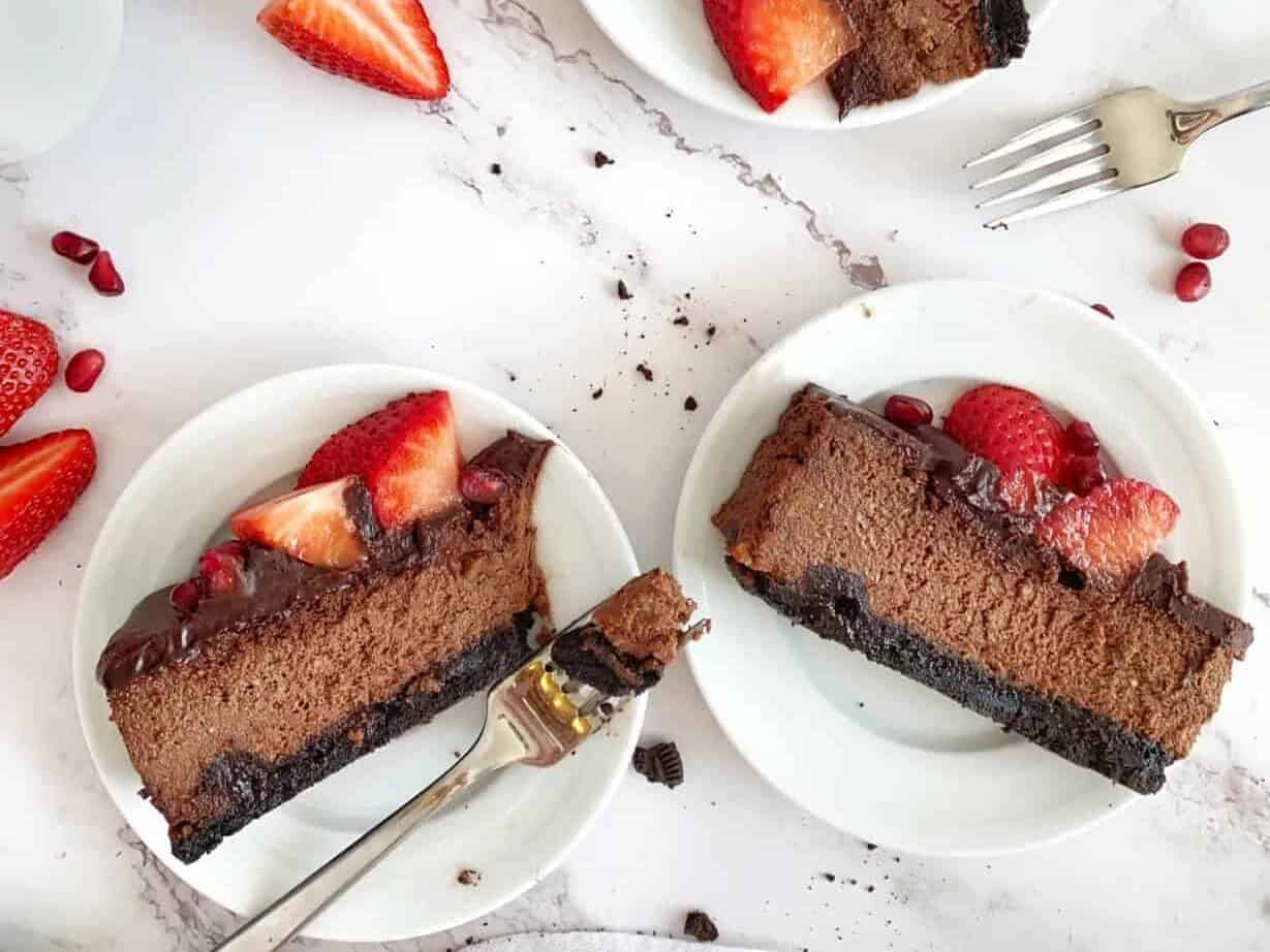 A slice of chocolate cheesecake with strawberries and raspberries.