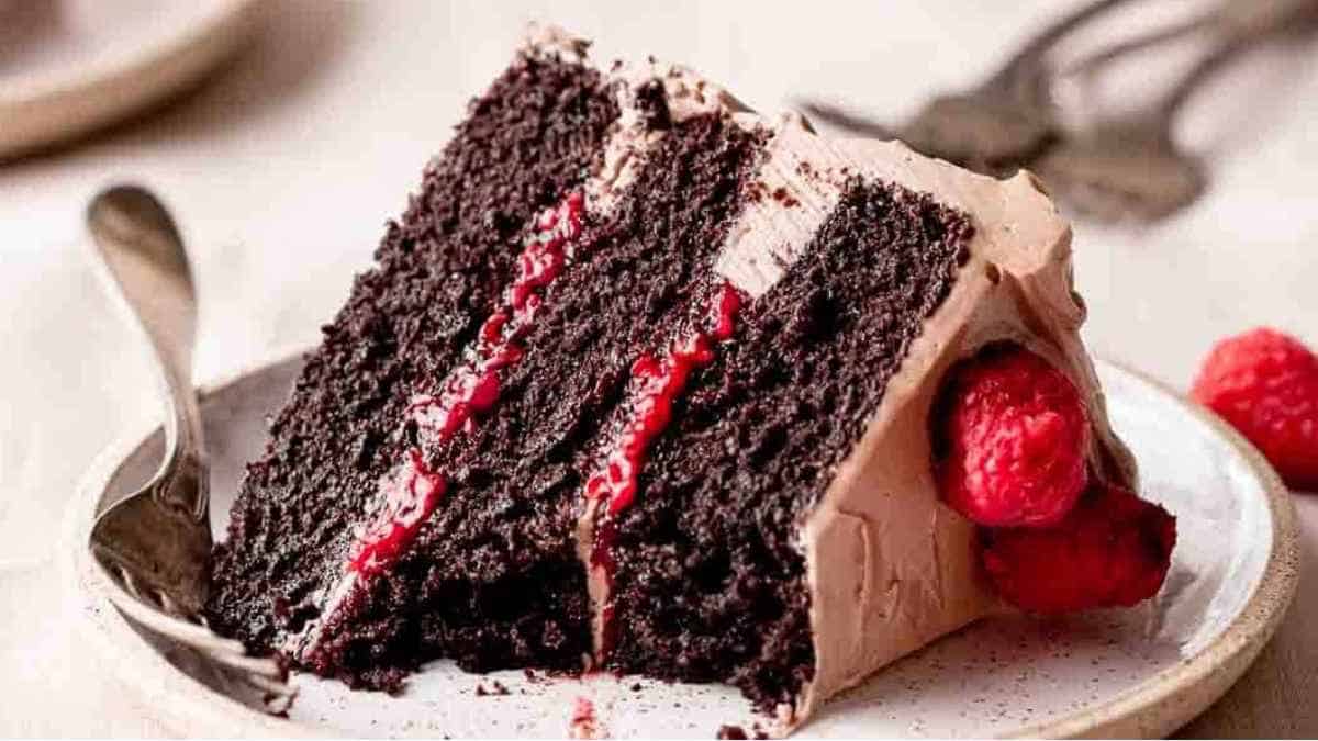 A slice of chocolate cake with raspberries on a plate.